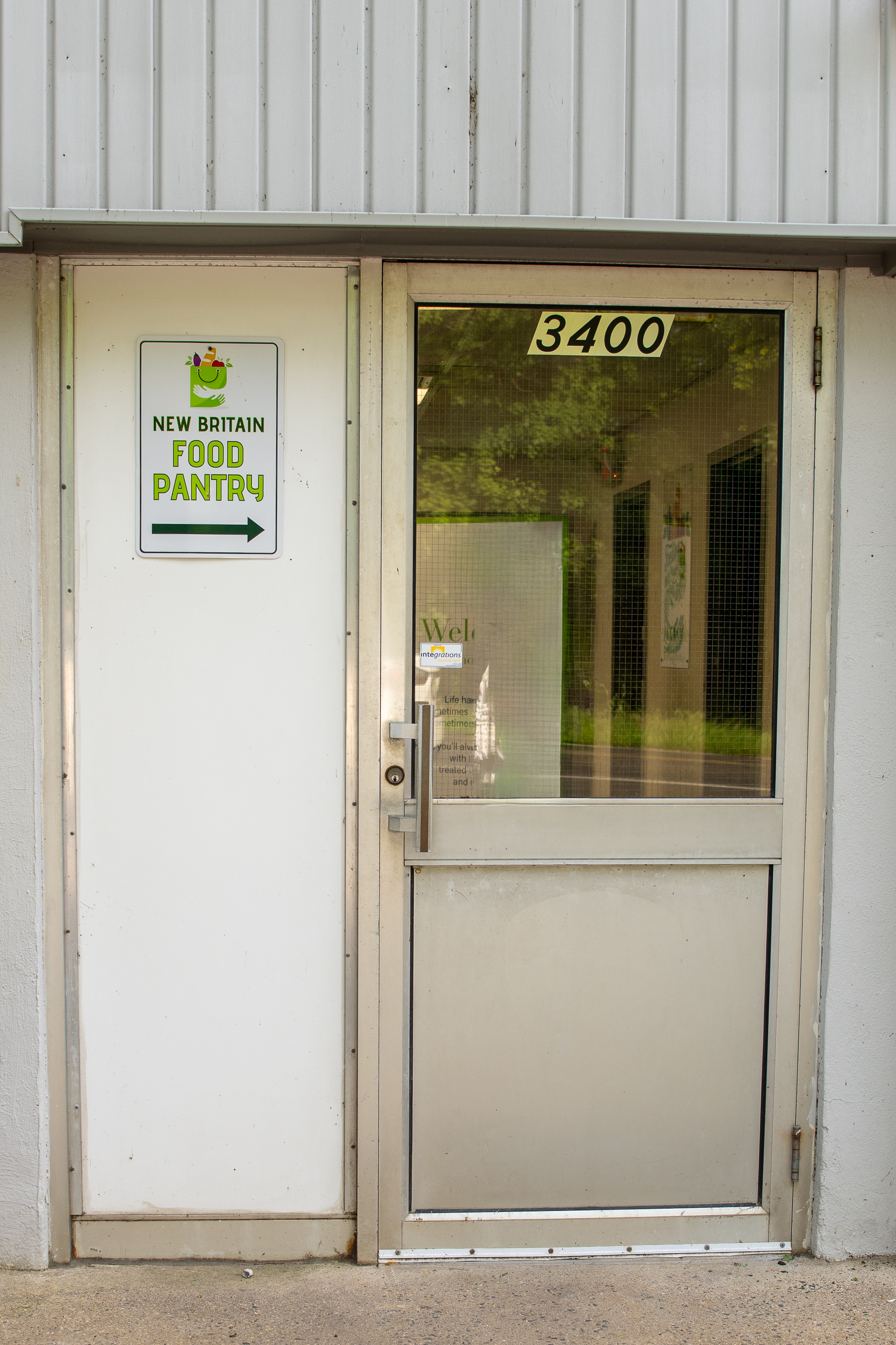 Side entrance with 3400 above the glass door and a New Britain Food Pantry sign pointing toward it.